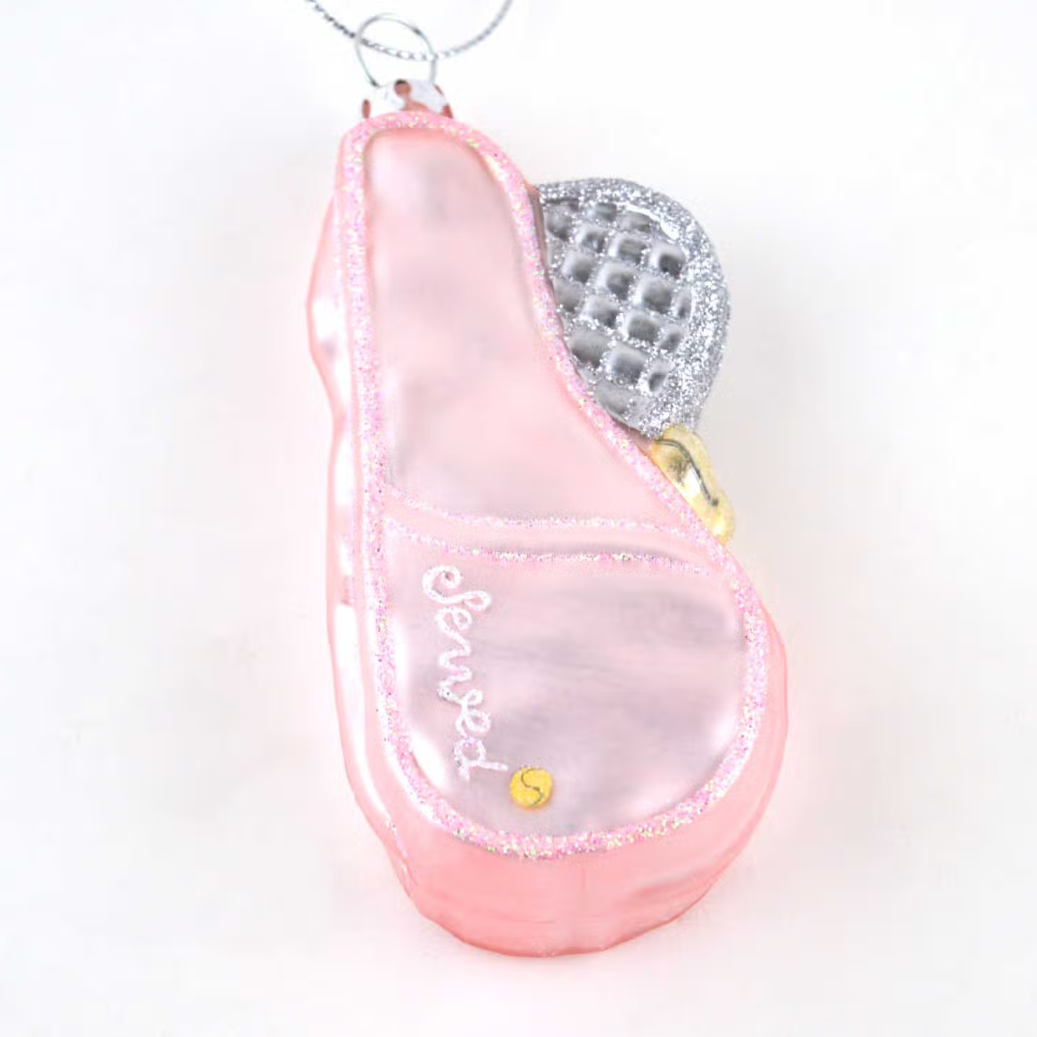 close up shot of pink tennis racket bag shaped ornament with a silver and glittery racket sticking out of the bag. Ornament had silver string