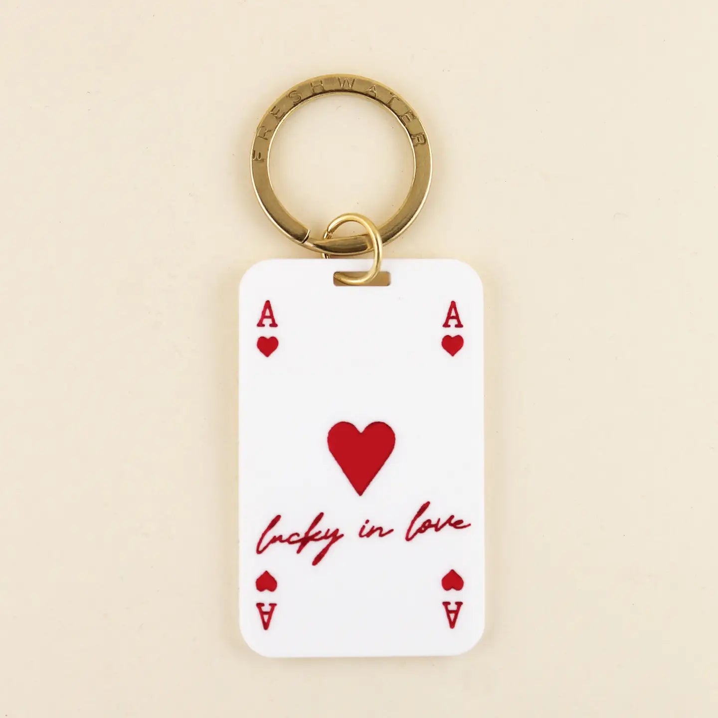 Keychain with playing card design featuring a heart and text on a beige background