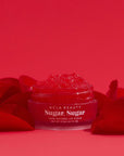 Red Roses Lip Scrub pot surrounded by rose petals on red background