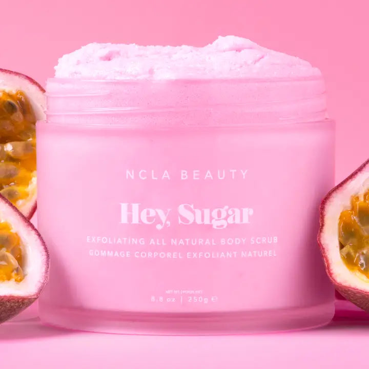 Pink jar of NCLA Beauty 'Hey Sugar' body scrub with passion fruit on a pink background