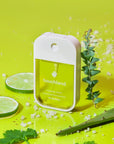 green hand sanitizer surrounded by limes and aloe plants