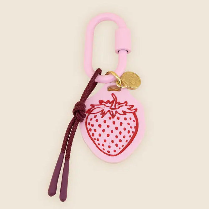 pink strawberry bag charm on a beige background