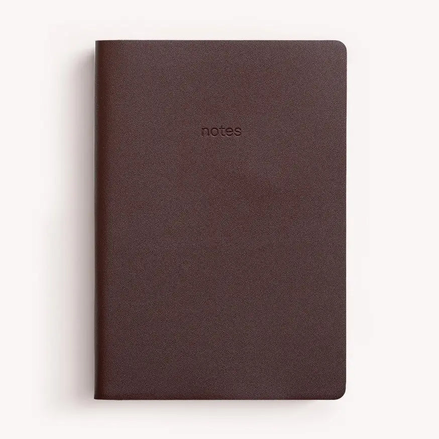 A dark brown textured notebook with a matte finish, featuring the word 'notes' embossed on the front cover, set against a clean white background.