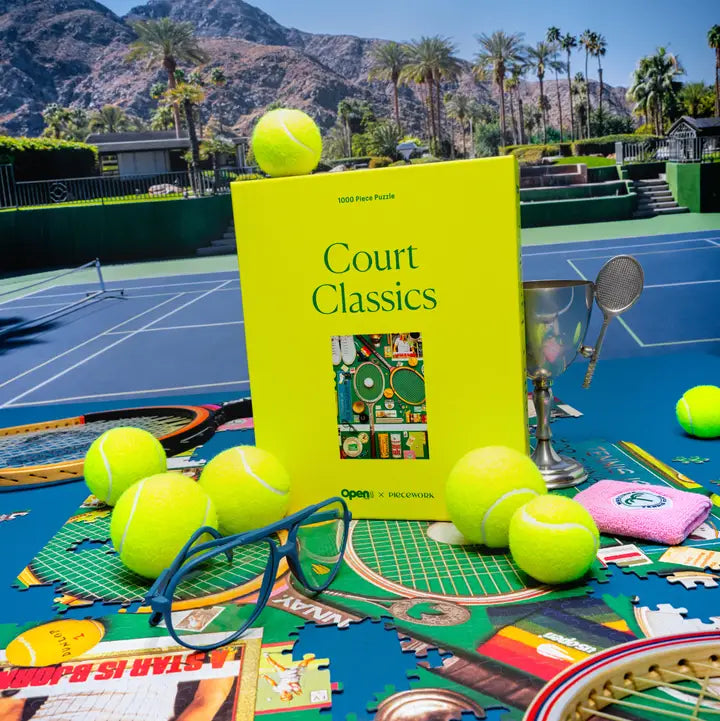 Book titled 'Court Classics' on a tennis court with tennis balls and other items.
