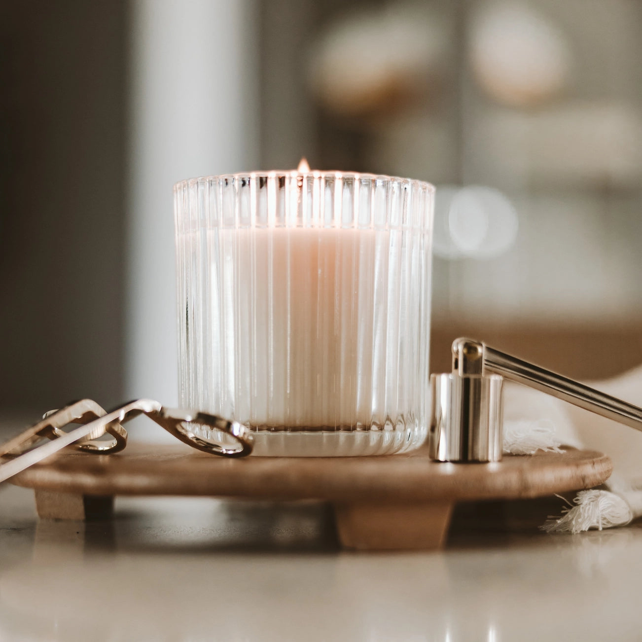 ribbed glass candle next to wick trimmer and candle snuffer