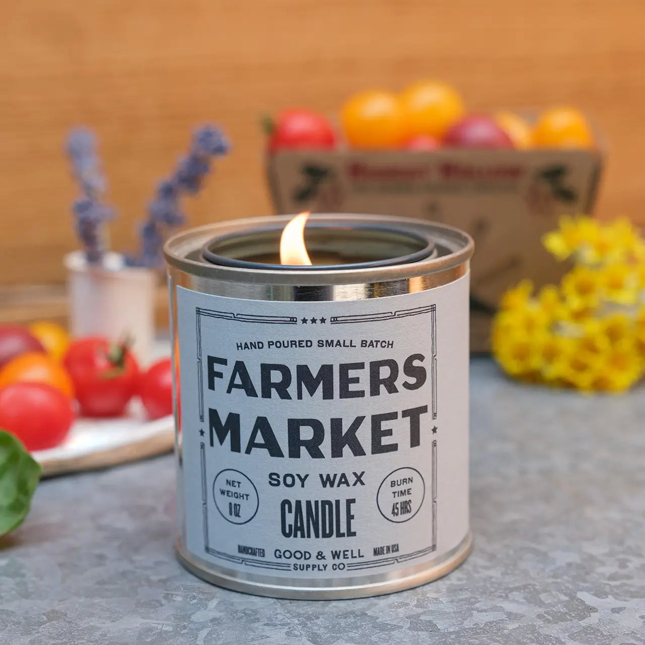 Farmers Market soy wax candle in a metal canister with a wooden background and fruits.