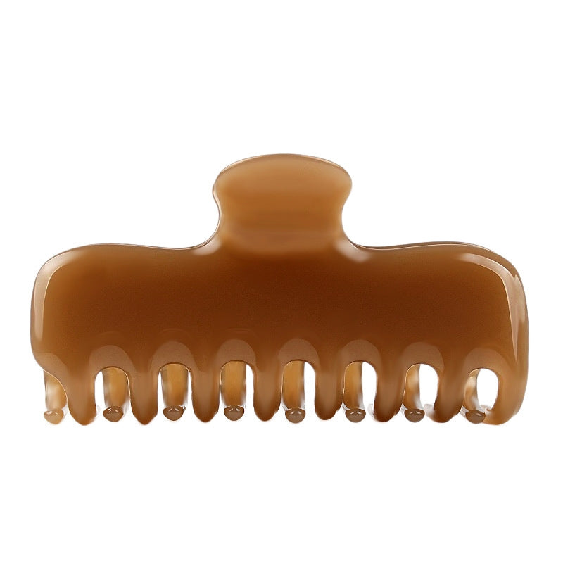 A glossy amber-brown hair claw clip shown from the side against a plain white background.