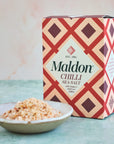 box of Maldon Chilli Sea Salt placed behind a bowl of the salt itself.