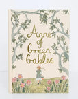 Book cover of 'Anne of Green Gables' with a girl and flowers on a beige background