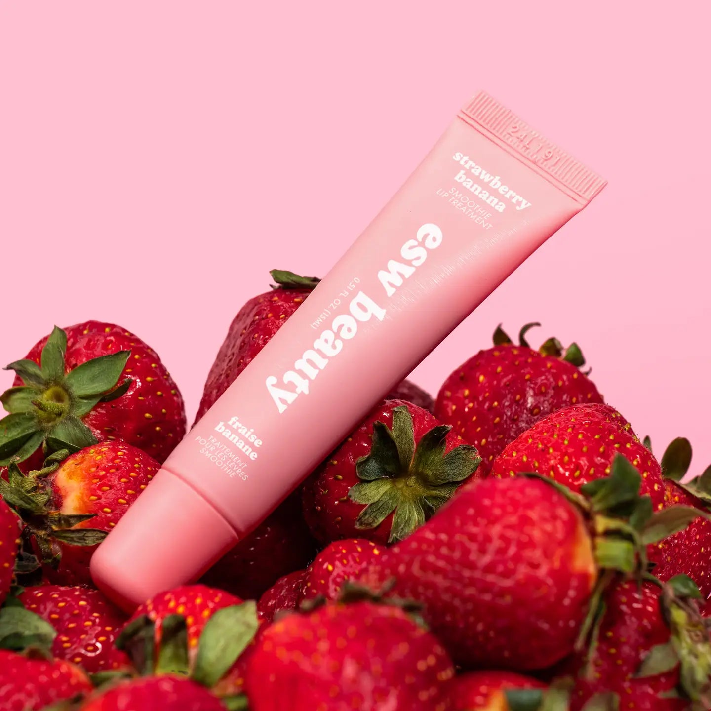 Pink lip balm with 'SWEET BERRY' text on a pink background with strawberries