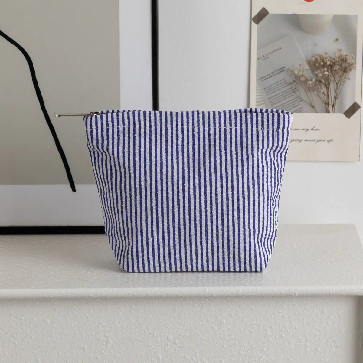 Blue and white striped pouch on a white surface with a neutral background