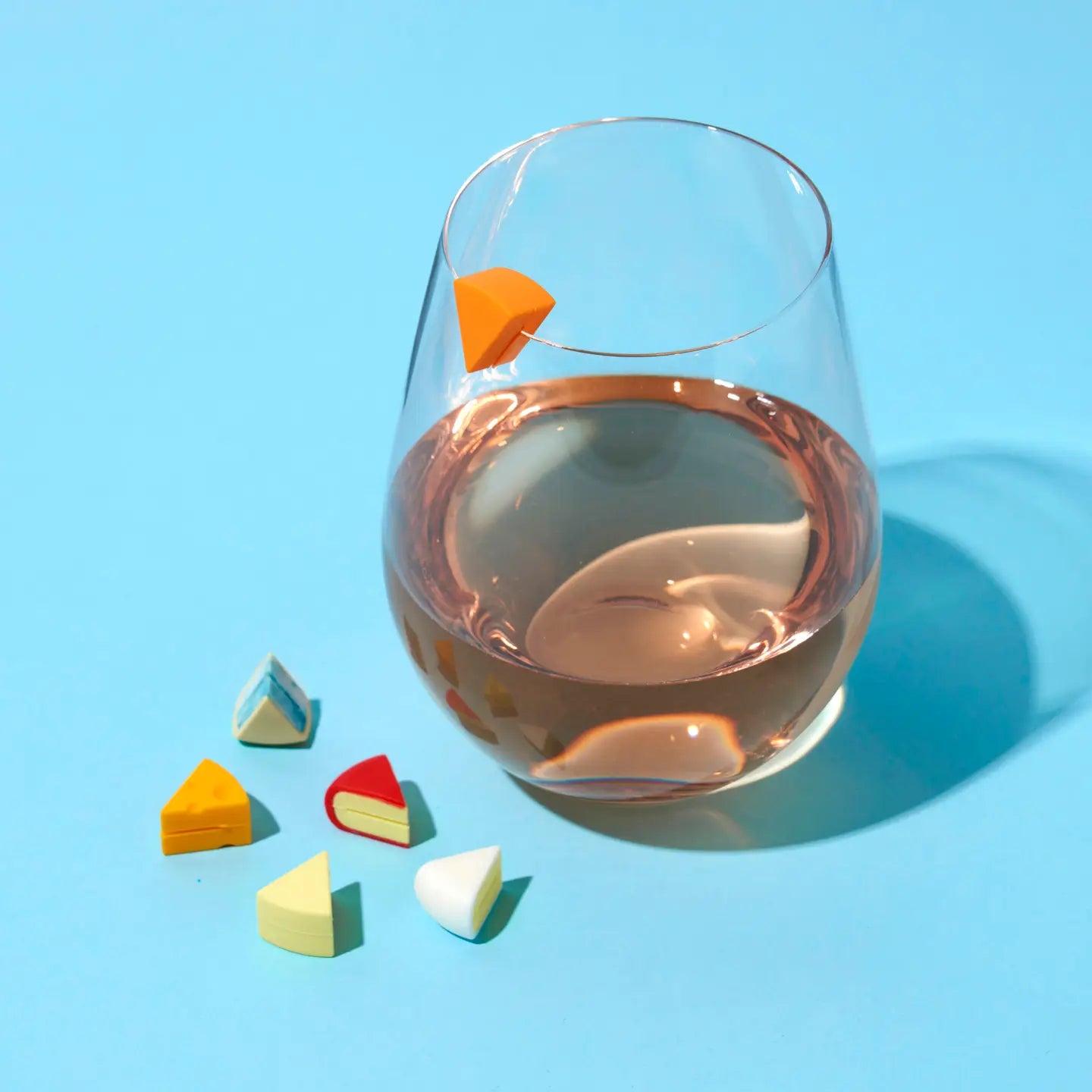 Glass of rose wine with colorful candy pieces on a blue background