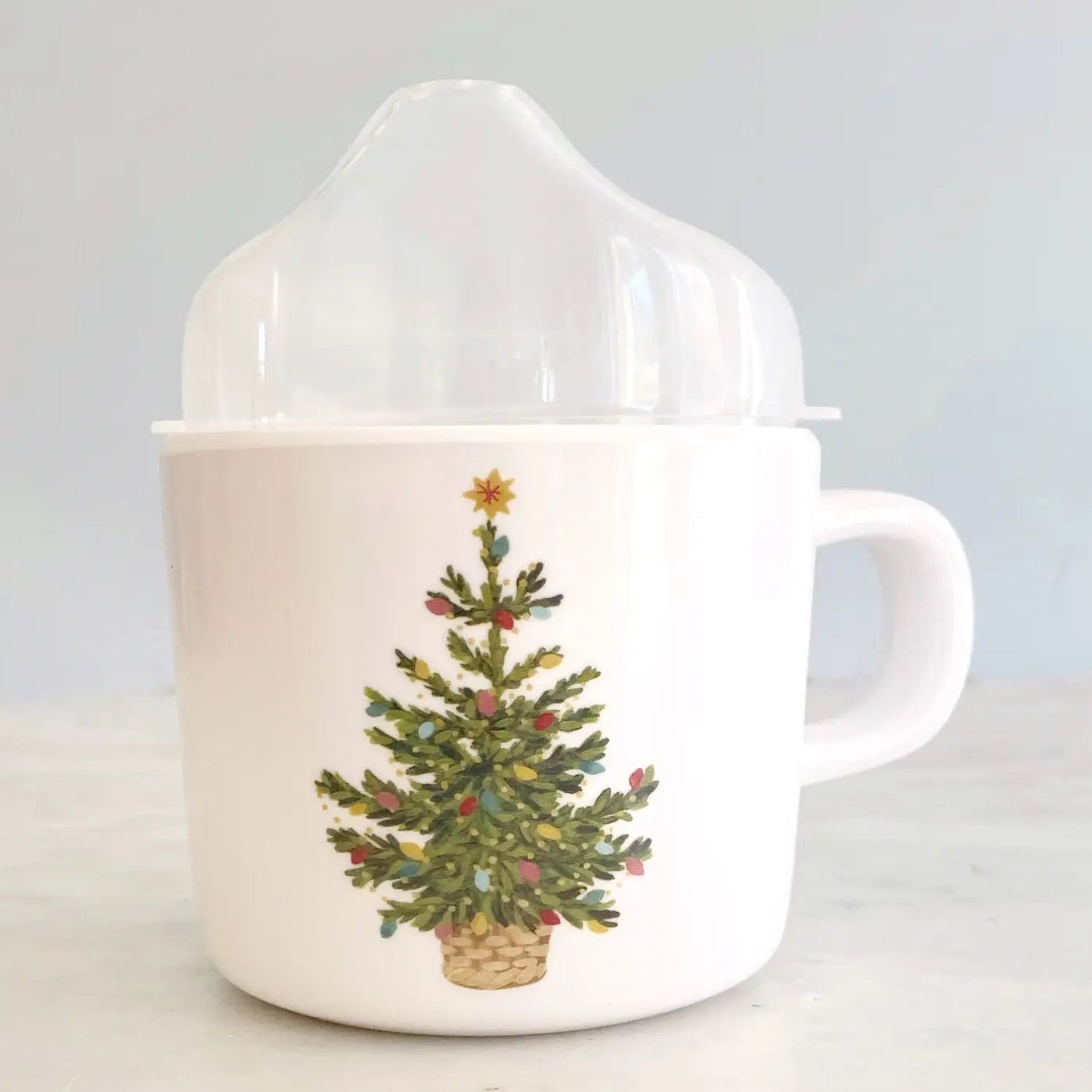 White mug with a Christmas tree design on a light gray background