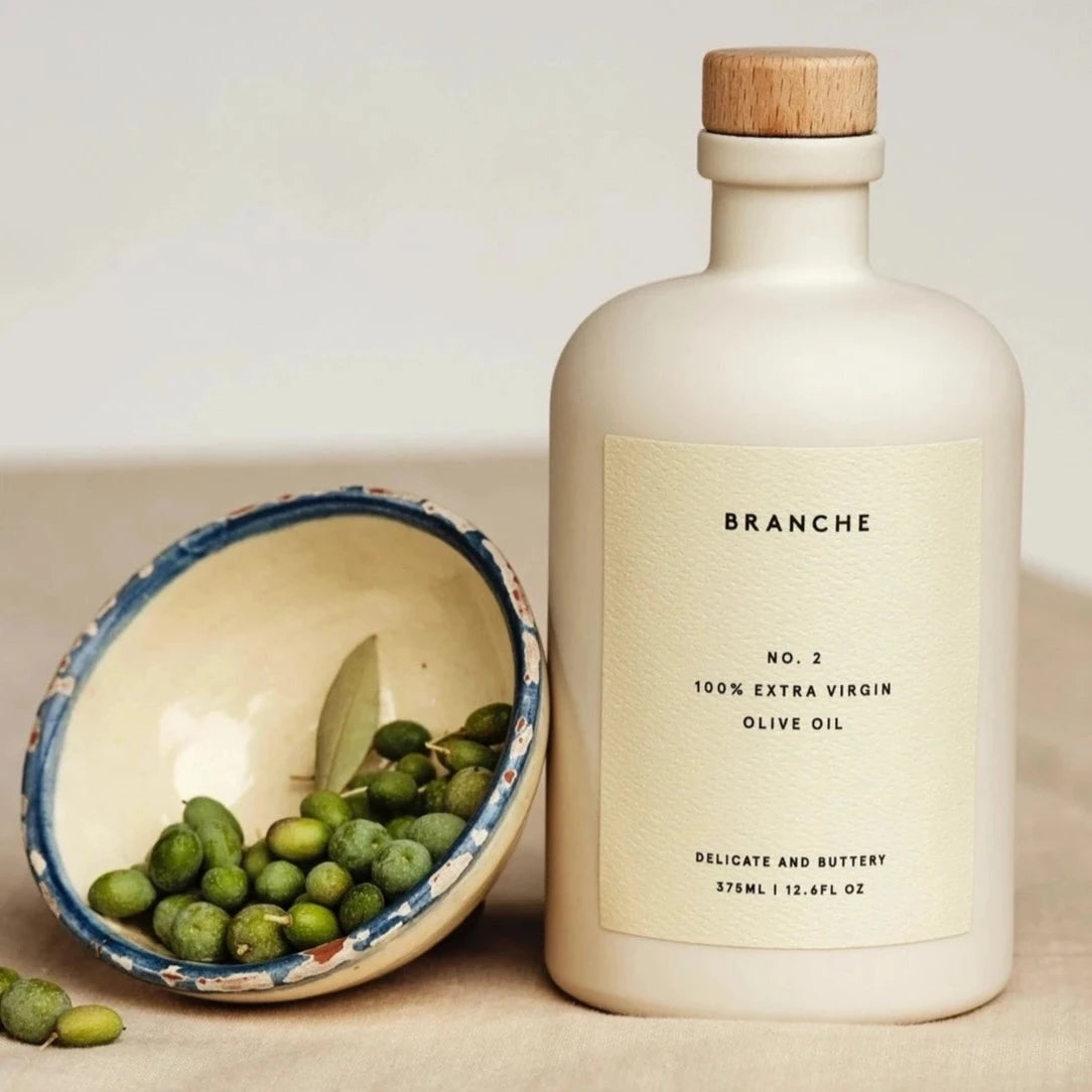 Beige olive oil with wooden cap. has yellow label with black text on the center