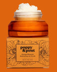 Orange lip scrub jar with floral design and 'Poppy & Pout' branding on an orange background