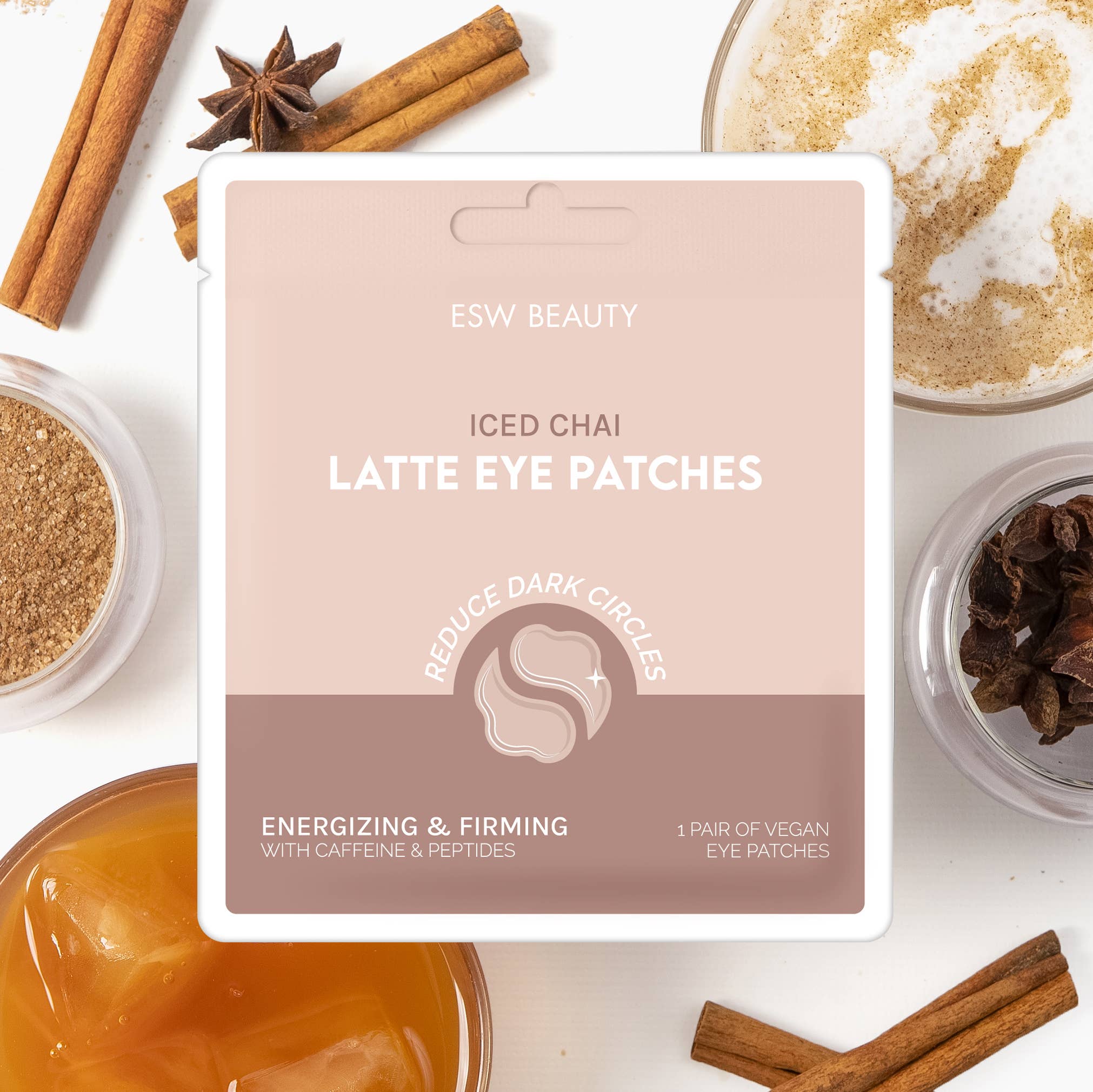 ESW Beauty Iced Chai Latte Eye Patches in a white and dusty pink packaging card, styled on a white background with cinnamon sticks, star anise, and coffee cups.