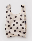 A reusable fabric shopping bag with a black polka dot pattern on a cream background, shown against a light gray studio backdrop.