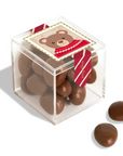 Clear cube box with chocolate eggs and a bear-themed label on a white background