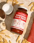 marinara sauce bottle sitting on counter surrounded by pasta 