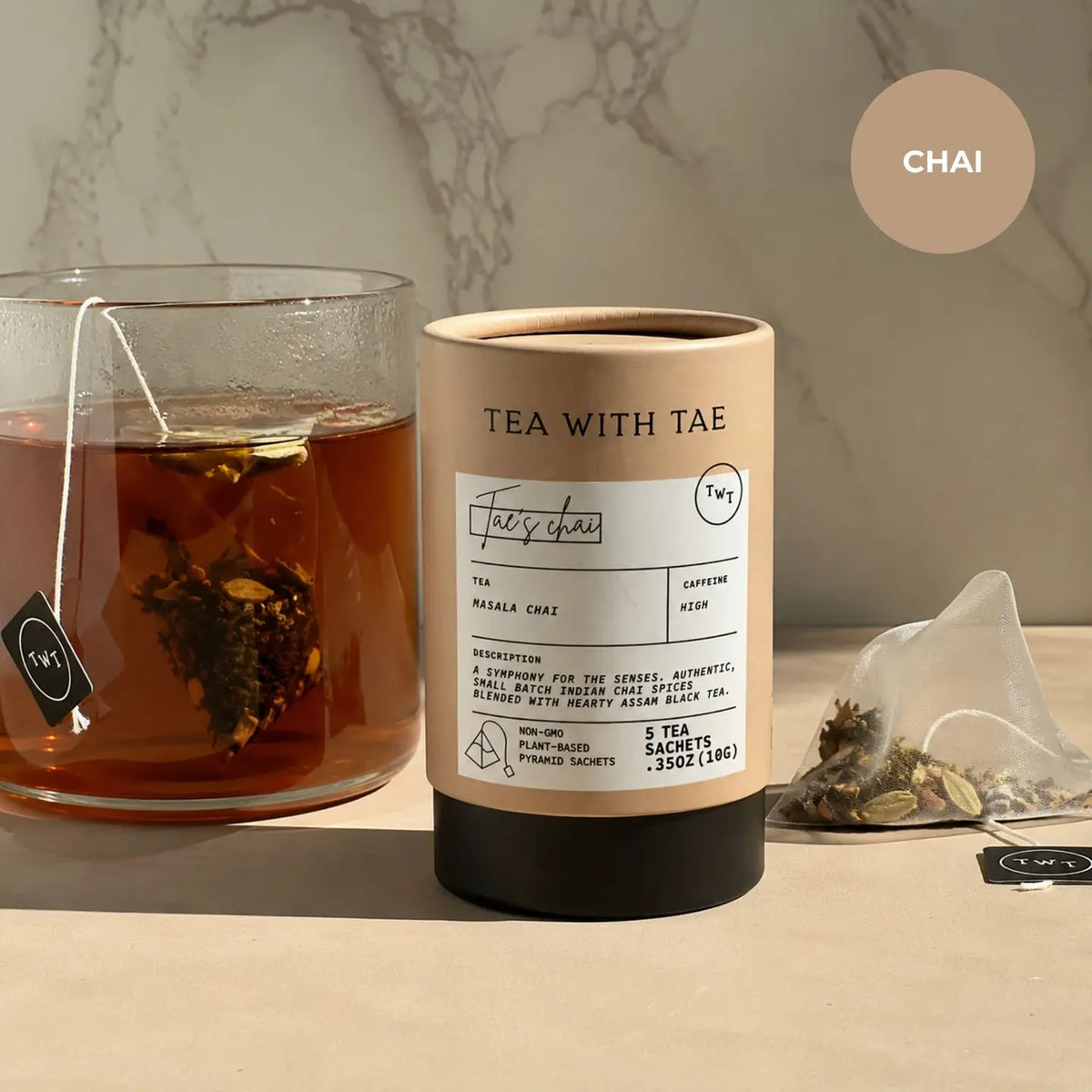 Tea canister labeled 'Tea with Tae' next to a glass of tea on a marble surface.