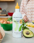 Bottle of Brightland salad oil on a kitchen counter with avocados and eggs.