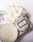A curated gift set in a light wood box featuring a round L'OUSEA Moroccan Ground soap tin with a white lace pattern, a large ivory satin scrunchie, a matching scalloped ivory dish, and a holographic iridescent pouch. The L'OUSEA brand label is clearly visible on the soap tin.