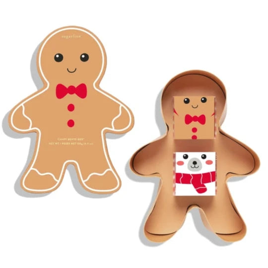 A gingerbread man-shaped gift box with a smiling face, red bow tie, and icing details. The box is shown closed on the left and open on the right, revealing two smaller candy boxes inside, one of which features a cartoon polar bear wearing a red scarf.






