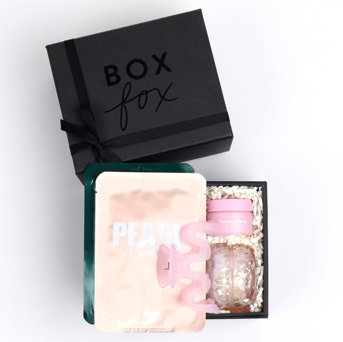 Mini Black BOXFOX gift box packed with 2 lapcos face masks, a pink squiggle hair clip, and ncla lip mask