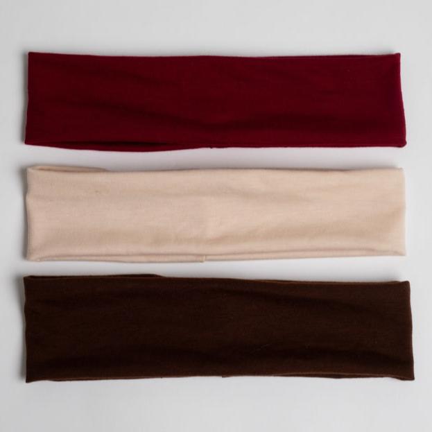 three headbands in different colors. The headbands are arranged in a vertical stack, with a burgundy headband on top, a beige or cream-colored headband in the middle, and a dark brown headband at the bottom. 