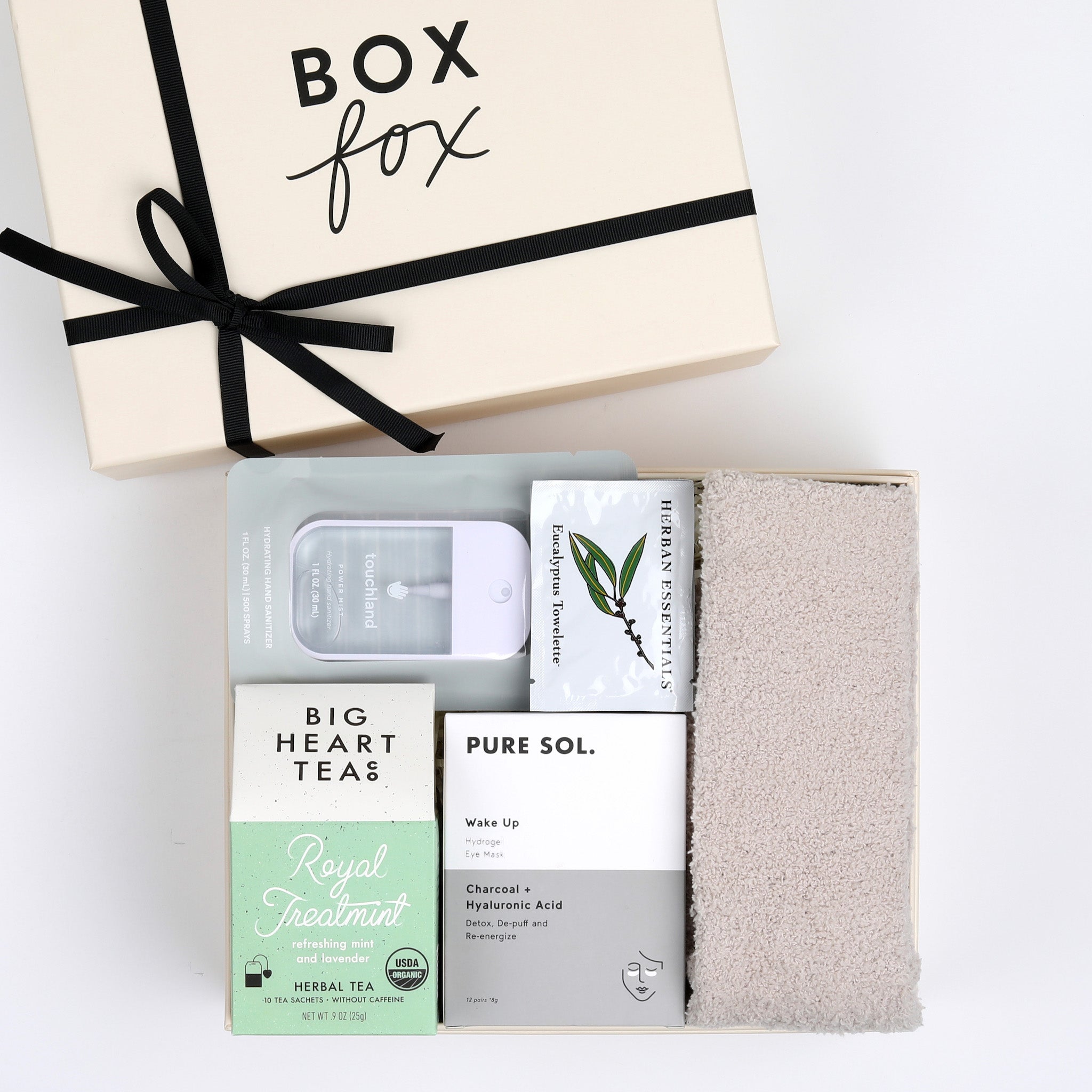 BOXFOX Creme Gift Box filled with Royal Treatmint Big Heart Tea, Pure Sol Charcoal Eye Pads, BOXFOX tan cozy socks, set of Herban Essentials Eucalyptus wipes and Touchland hand sanitizer