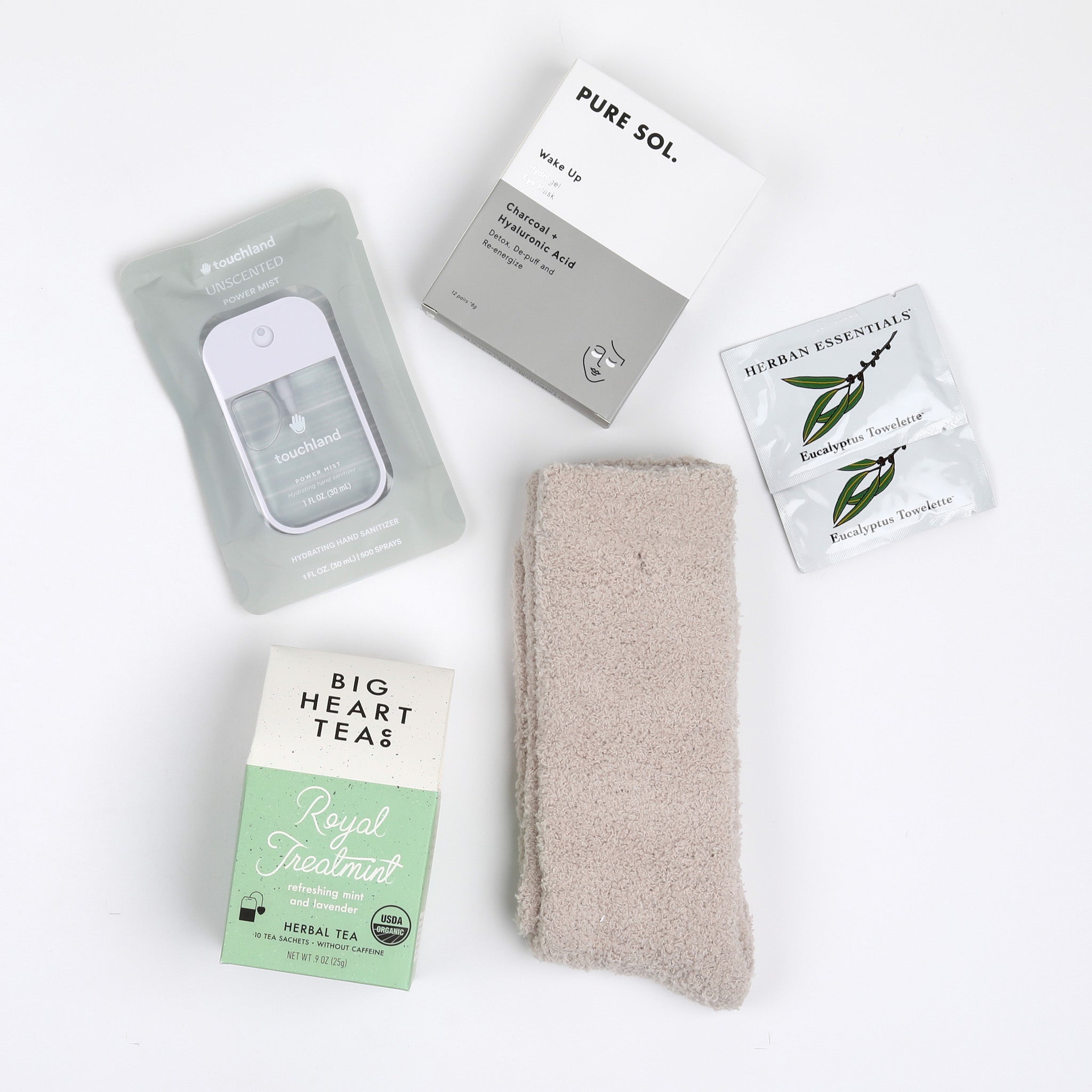 BOXFOX Creme Gift Box items including Royal Treatmint Big Heart Tea, Pure Sol Charcoal Eye Pads, BOXFOX tan cozy socks, set of Herban Essentials Eucalyptus wipes and Touchland hand sanitizer laid out on white background