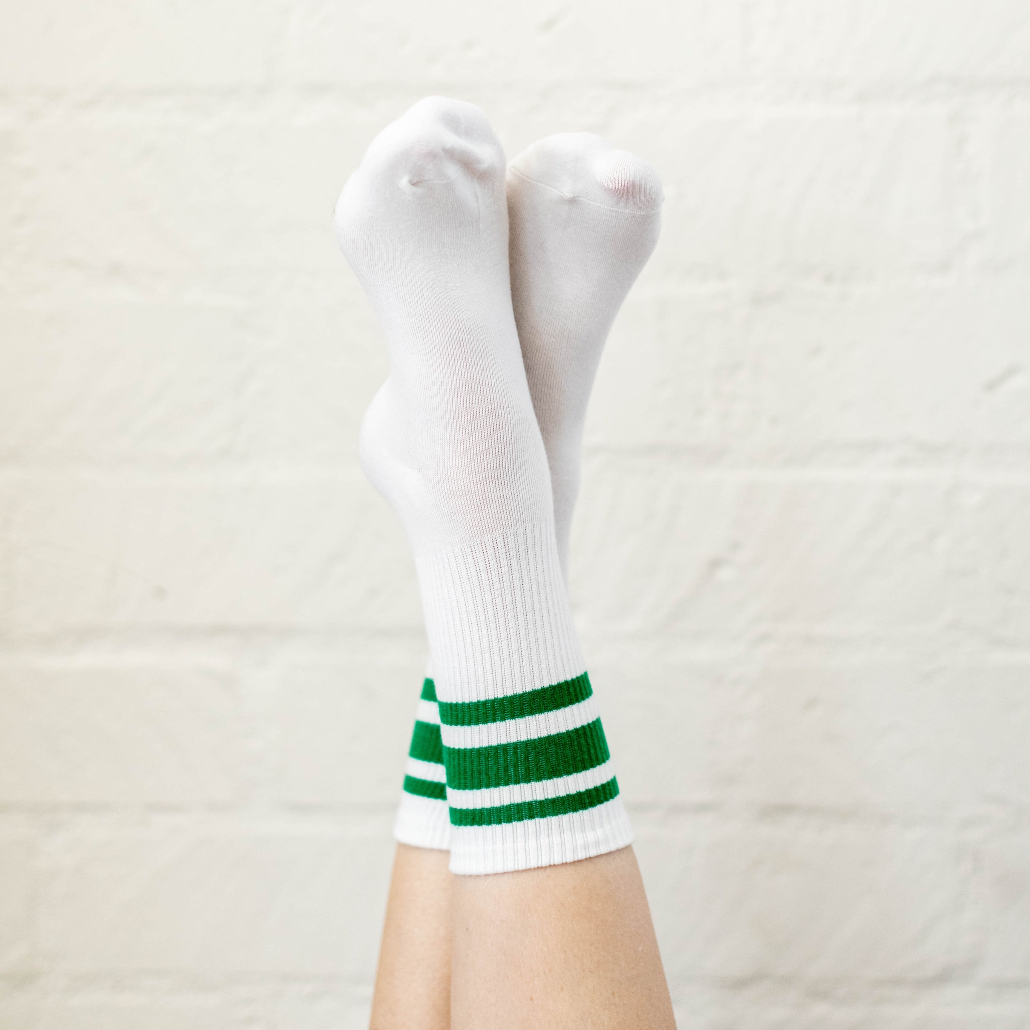 white socks with green stripes on criss crossed feet