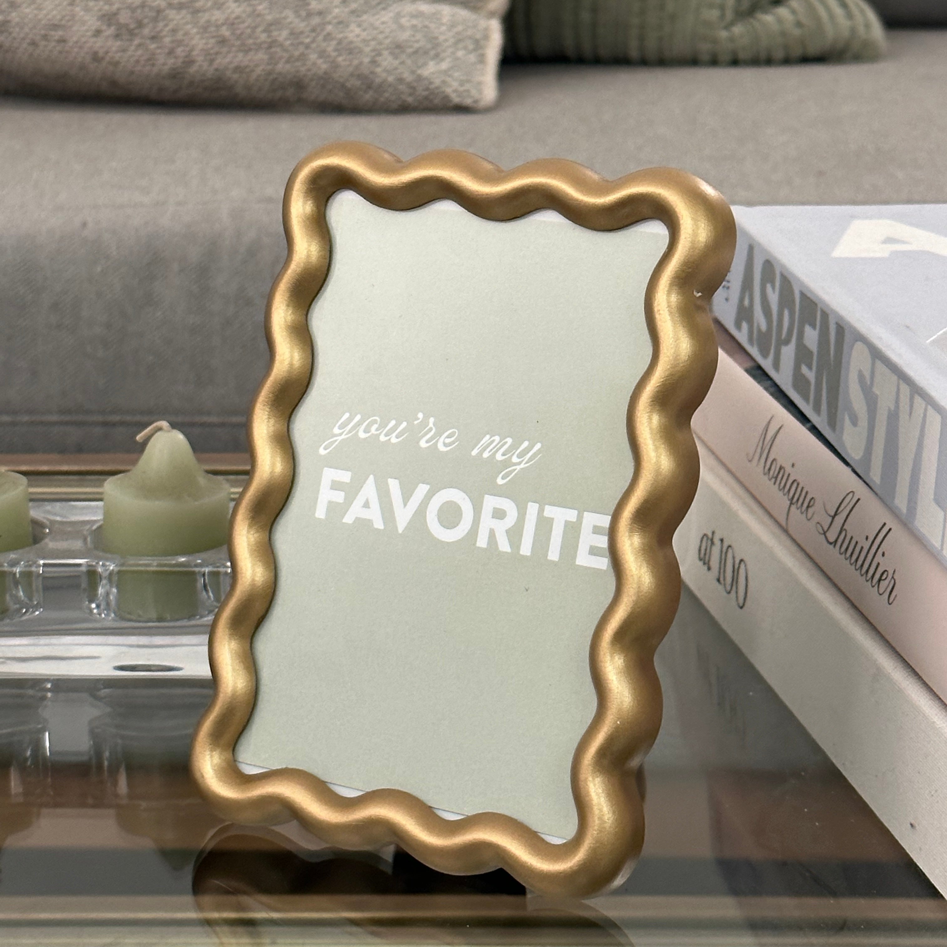 a wavy gold frame sitting on a glass coffee table