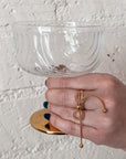 Gold bow ring on hand holding champagne coupe