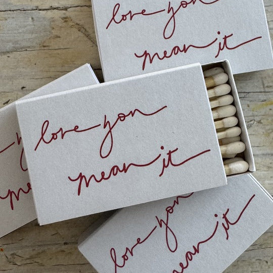 Matches in a box with 'love you mean it' text on a wooden surface