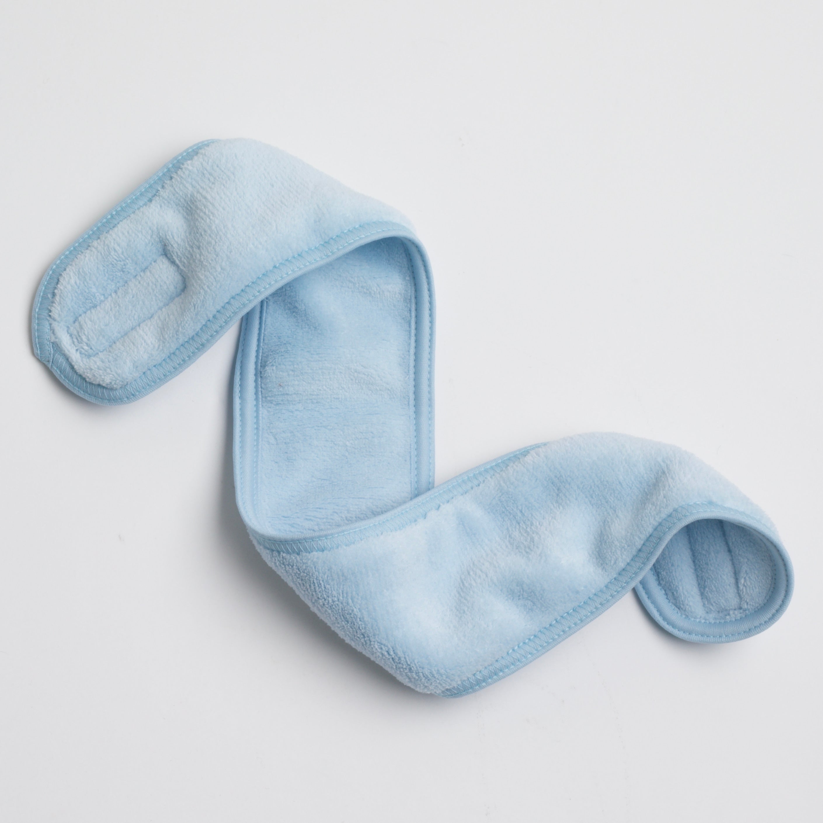 soft, plush spa headband in icy blue color, displayed on a white background