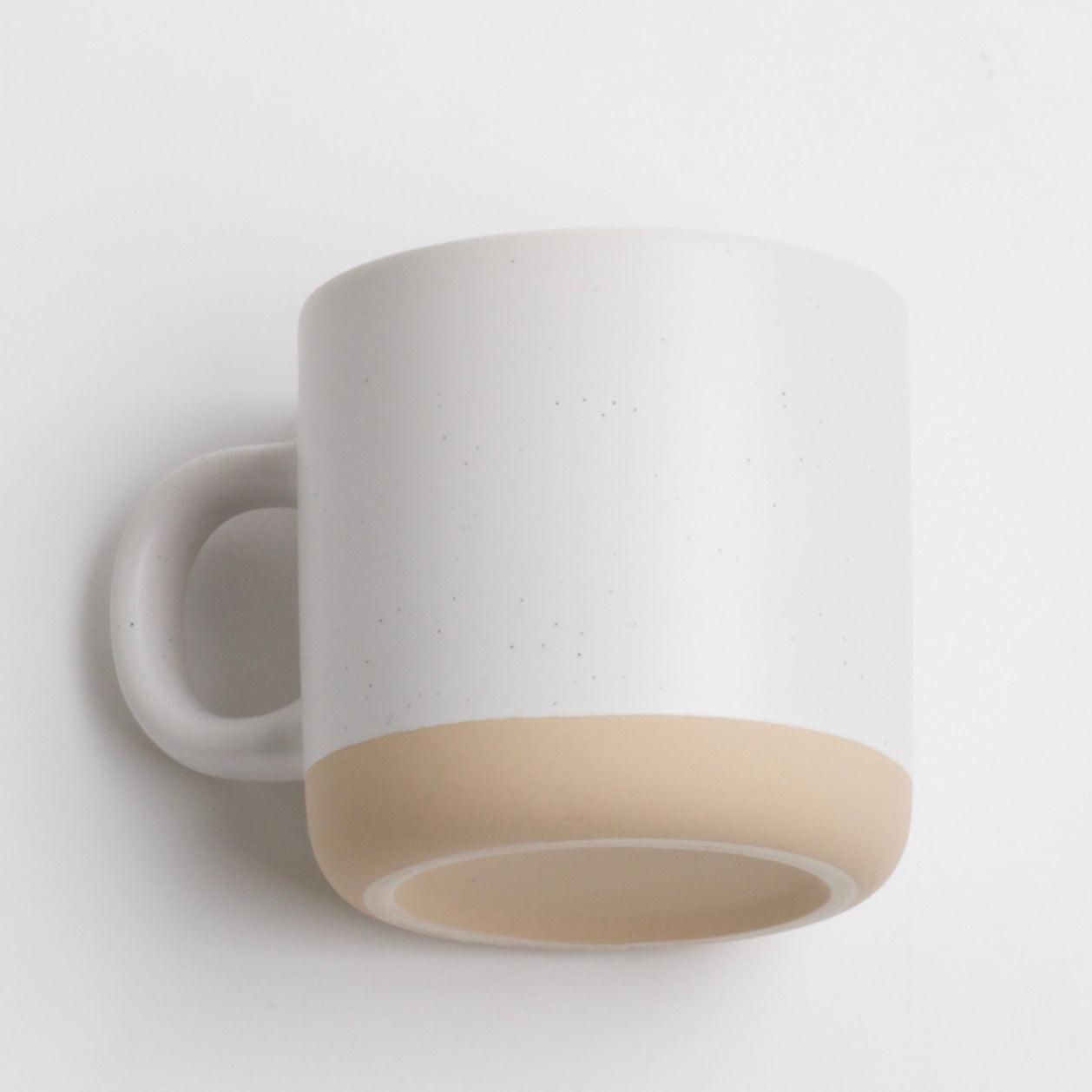 white mug with black speckles and a beige bottom