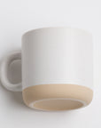 white mug with black speckles and a beige bottom