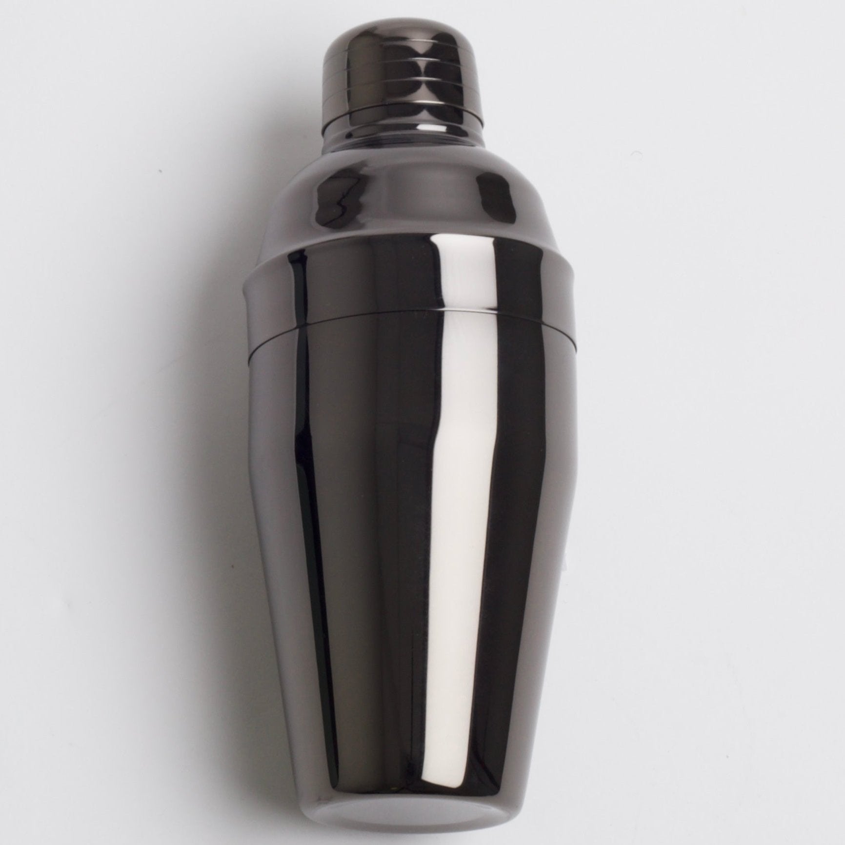 A sleek  dark, metallic gray cocktail shaker with a polished, reflective finish, shown assembled with its cap on.