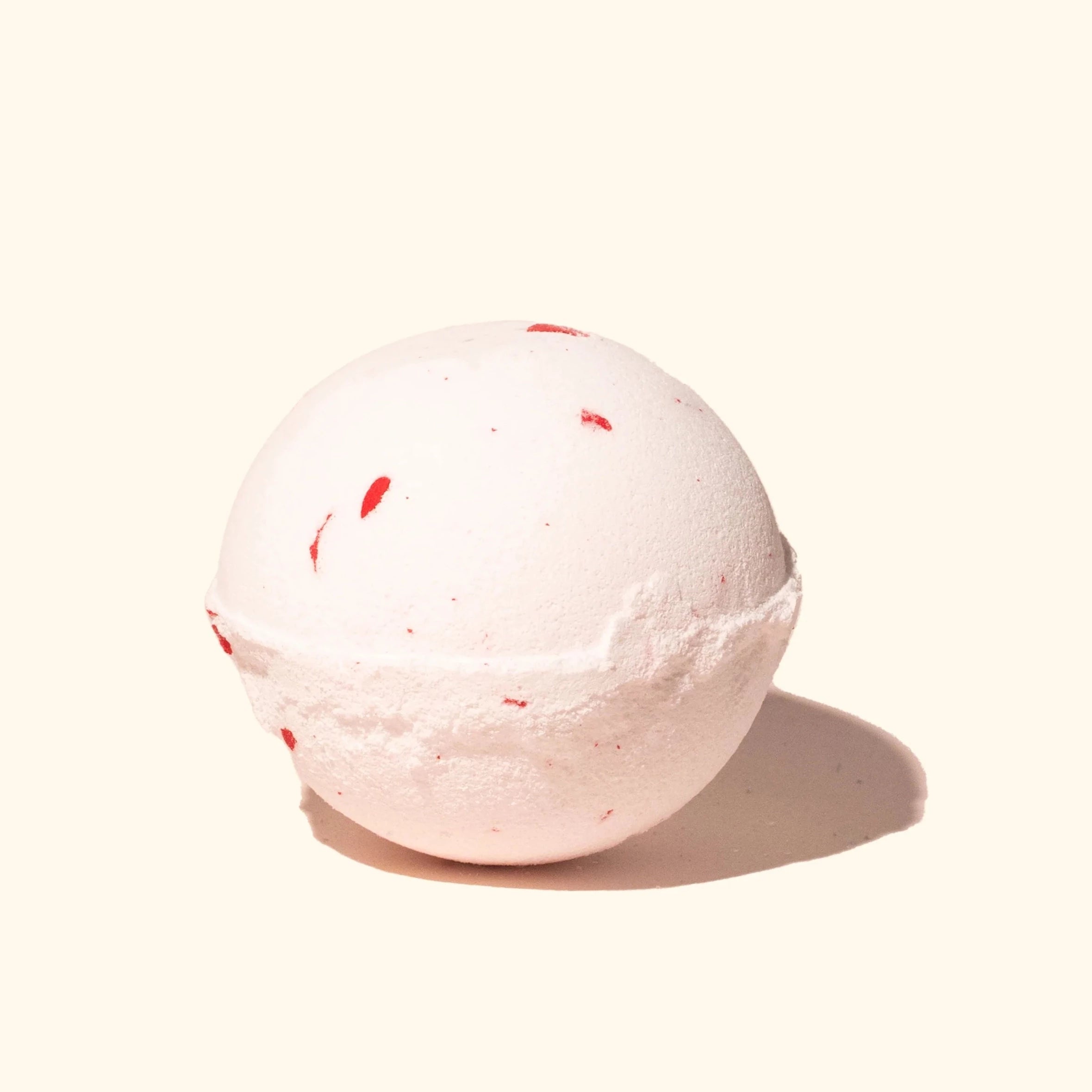 white bath bomb with red specks in it