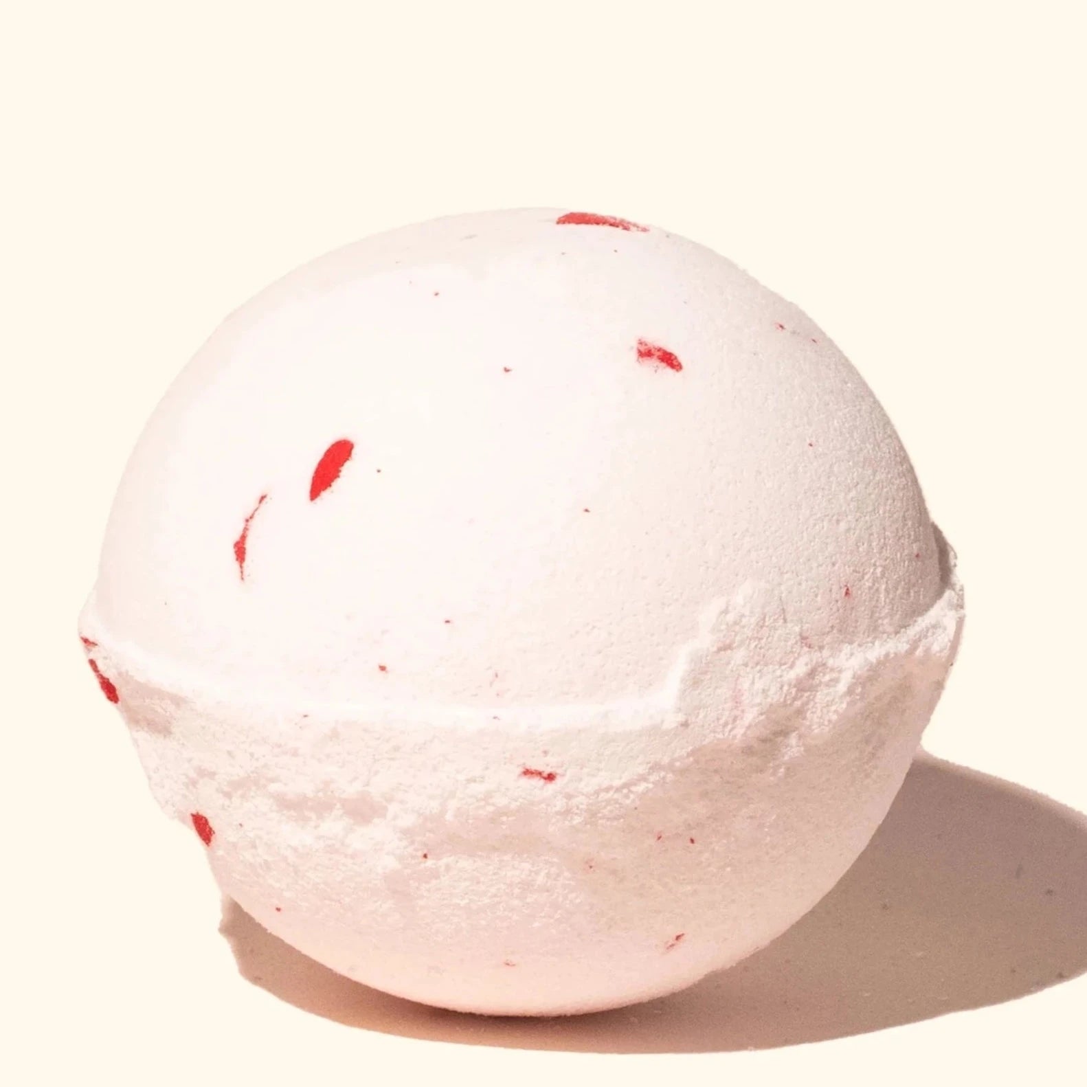 white bath bomb with red specks in it