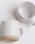 white mug with black speckles and a beige bottom