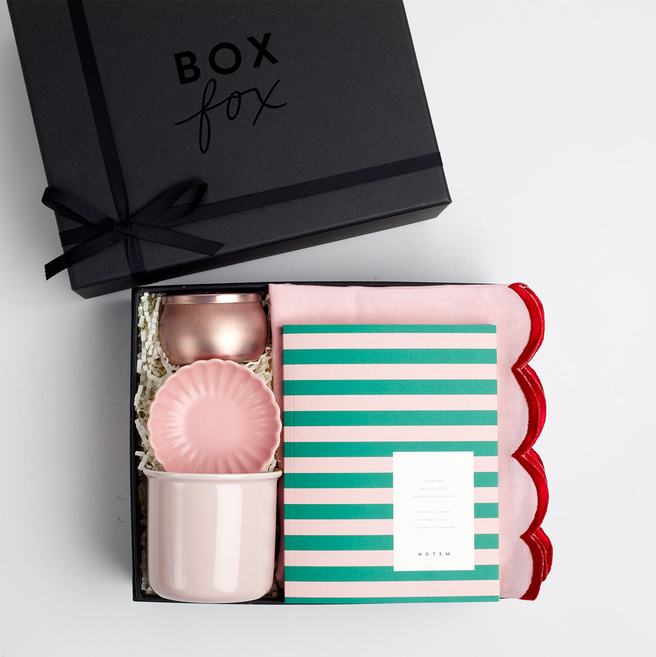 BOXFOX Black gift box packed with voluspa sparkling rose candle, pink scallop trinket tray, pink mug, green and pink stripe notem and pink two tone scallop tea towel