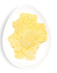 A white, oval-shaped dish containing a pile of yellow, bear-shaped gummy candies. The candies are lightly dusted with sugar, giving them a sparkly appearance.