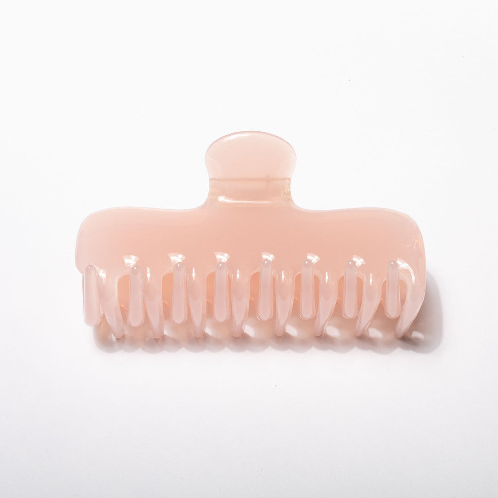 A translucent pale pink hair claw clip on a clean white background.