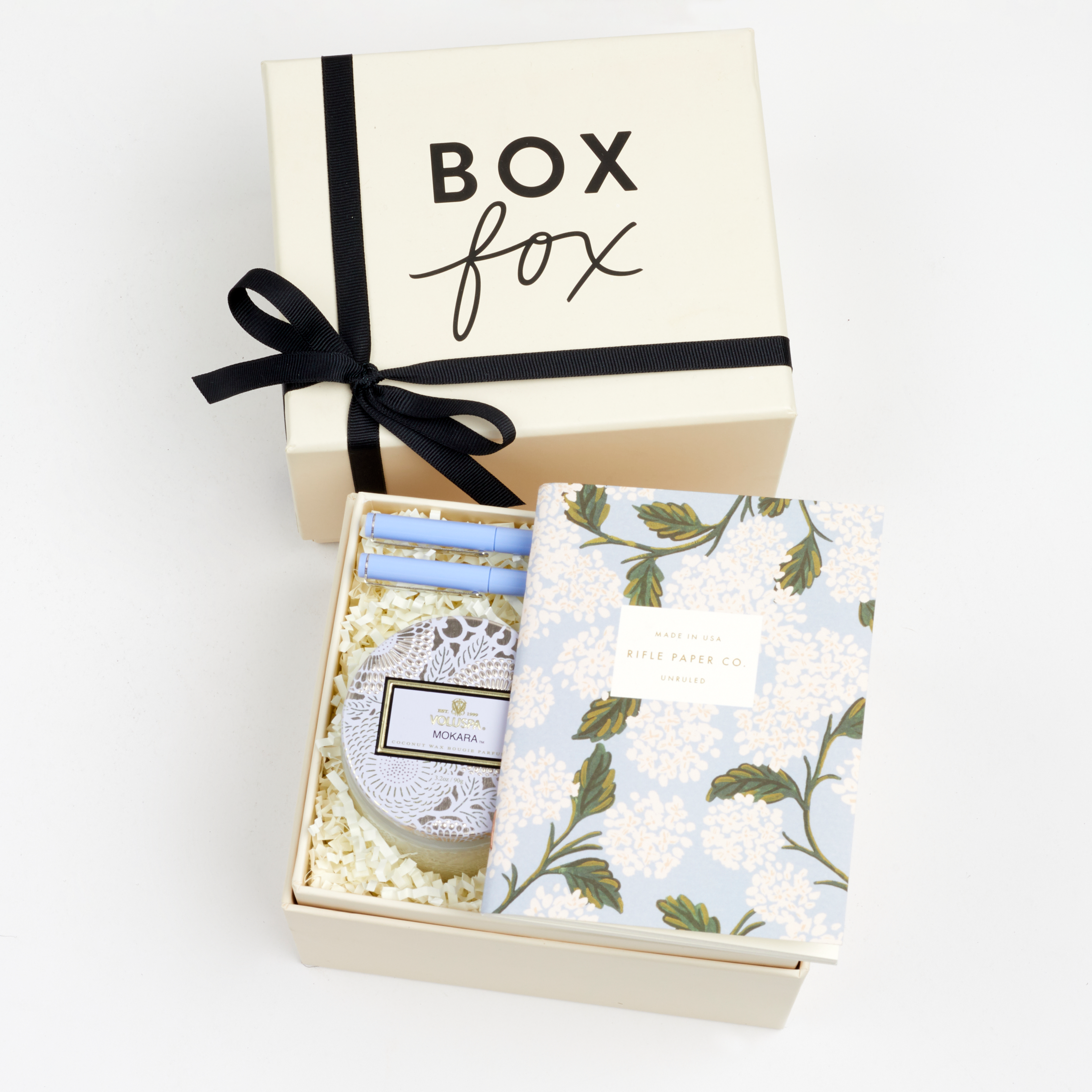 BOXFOX Original Creme Gift Box containing Rifle Paper Hydrangea Pocket Notebooks, 2 Periwinkle Le Pens, and Voluspa Mokara Petite Glass Jar Candle.