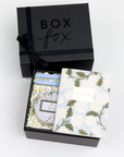 BOXFOX black Gift Box containing Rifle Paper Hydrangea Pocket Notebooks, 2 Periwinkle Le Pens, and Voluspa Mokara Petite Glass Jar Candle.