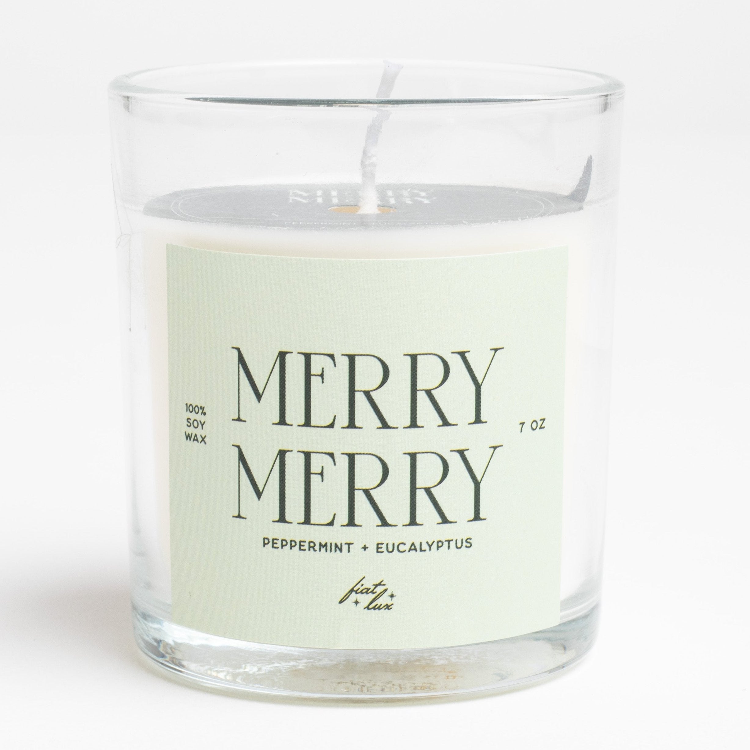 glass candle that has a light green label that says "MERRY MERRY" on it