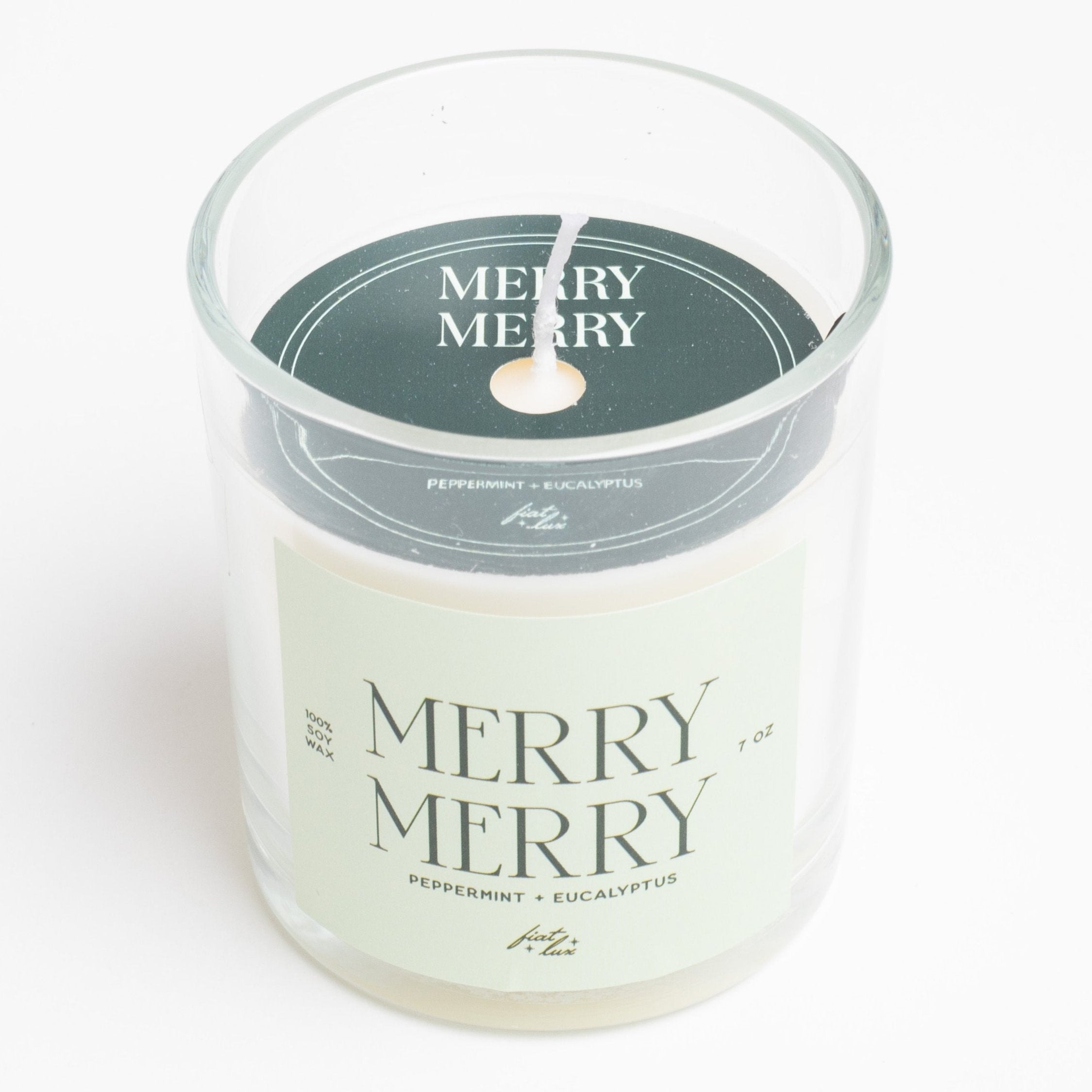 glass candle that has a light green label that says "MERRY MERRY" on it