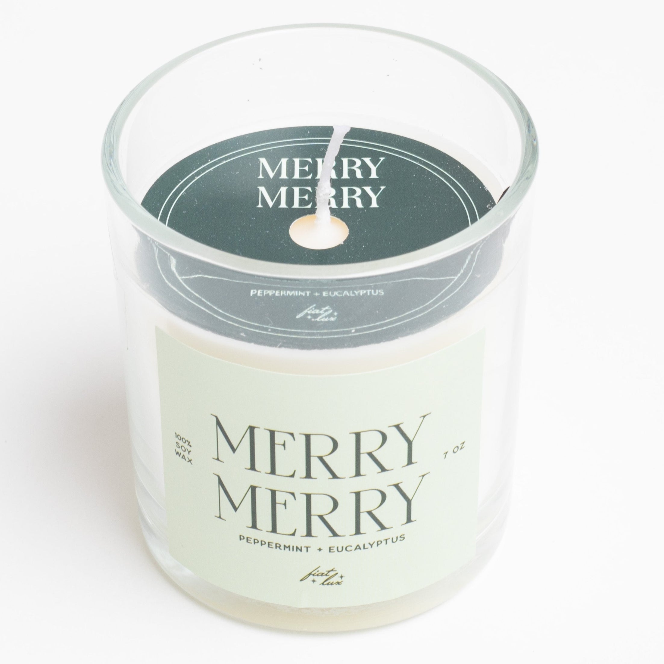 Candle in a glass jar with 'Merry Merry' label on a white background